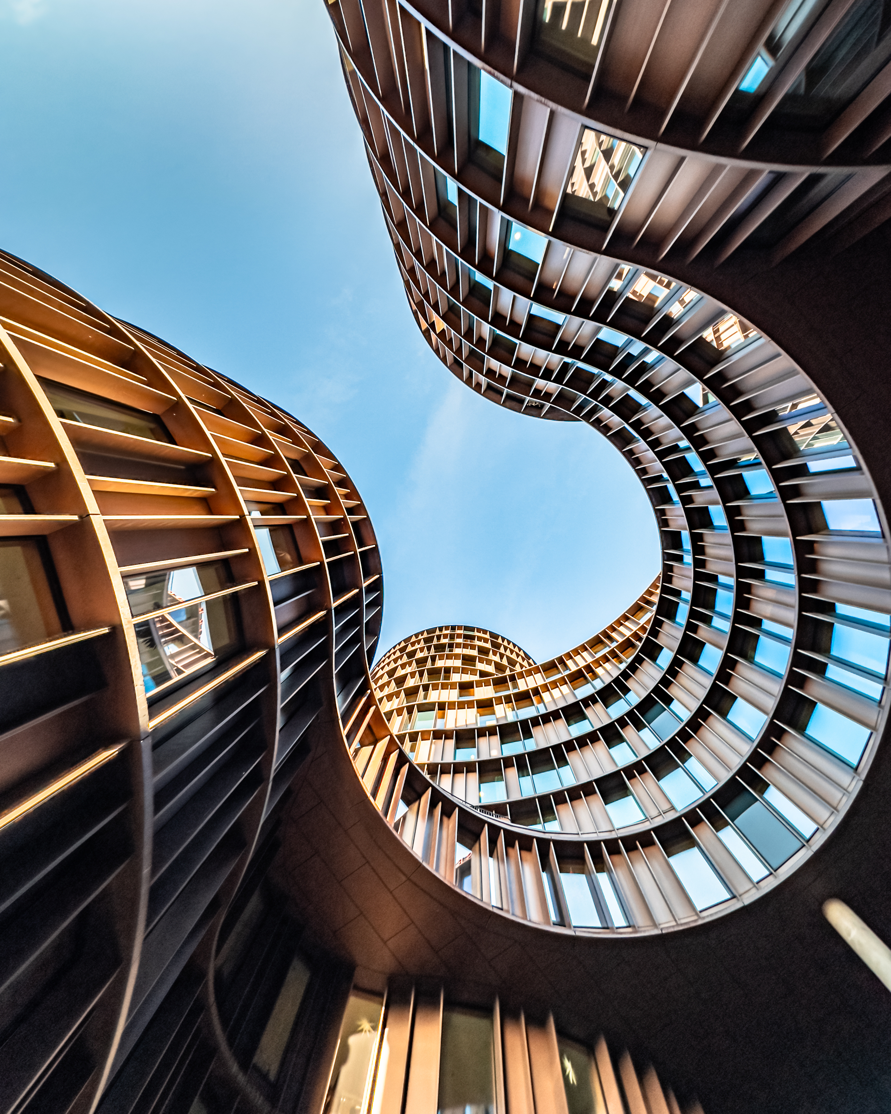 Upward view of curved buildings framing the sky — Fireflies Industry Advisory